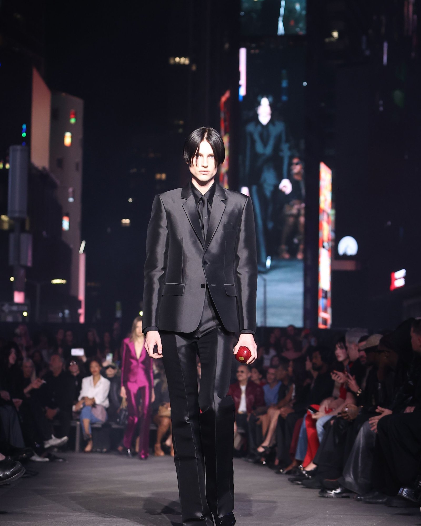 Gucci Cruise 2027 — opener carrying the red apple, Times Square.